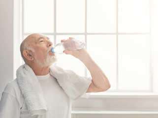 Thirsty senior man drinking water from bottle