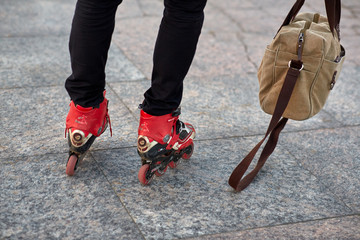 the guy rides on rollers after work. in a jacket and sports style. healthy lifestyle. legs and bag...