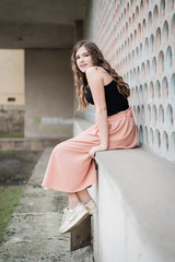 Portrait of a beautiful teenage girl. Happy hipster woman having fun on interesting city background. Pretty teenage girl. Fashionable portrait of beautiful girl. Model. Fashion. Look sideways.