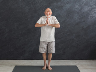 Meditating senior man with praying hands indoors