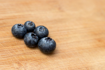 5 Ripe Blueberry close-up on wooden background with open space on one side