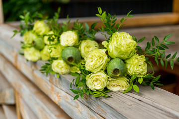 flowers of green roses in a bouquet with a green poppy head lie on the banisters