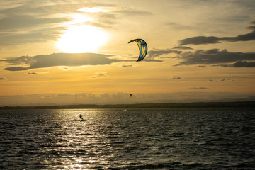 Un kitesurfer sous un coucher de soleil