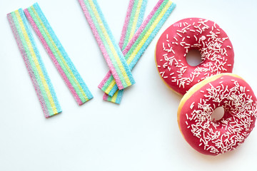 White and pink donuts and jelly candies on the white background isolated. Copy space.