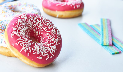 White and pink donuts and jelly candies on the white background isolated. Copy space.
