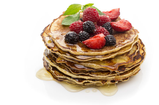 Delicious pancakes with berries and maple syrup top view, white background
