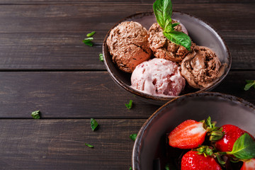 Portion of ice cream and strawberry on wood