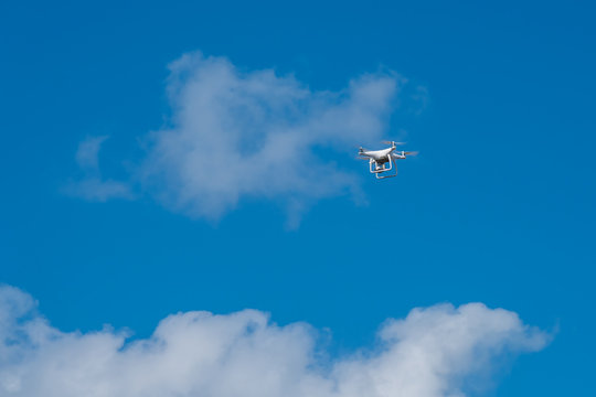 white drone hovering in a bright blue sky, Radio control helicopter with camera