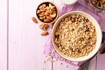 Bowl with granola on pink wooden background.