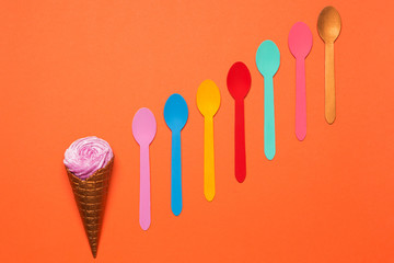 a horn with ice cream or with a cream and many multicolored spoons are lined up with a ledge, a concept