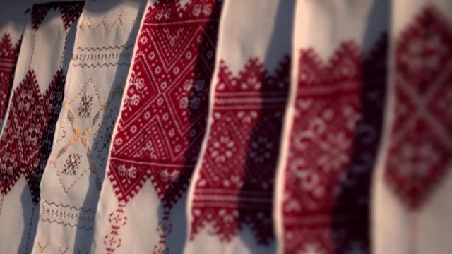 National Ukrainian rushnyk in warm sunlight. A symbol of Ukraine, traditional ethnic towel with hand embroidered ornament pattern. White cloth with multicolor needlework texture, close-up. 