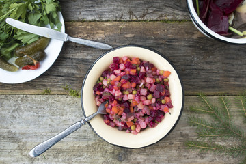 Vinaigrette is located on a wooden table, as well as pickled cucumbers and greens and cleaning leftover from the preparation of vinaigrette.
