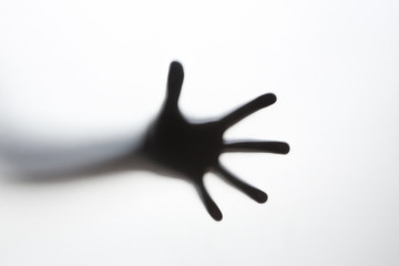 Hand silhouette behind a glass
