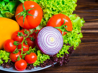 Close up of appetizing still life. Fresh bulgarian yellow pepper, cherry tomatoes, lettuce leaves, red onion, green basil on wooden board.