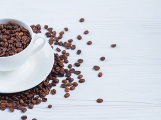 Porcelain white coffee cup and roasted beans on shabby wooden background. Top view. Copy space