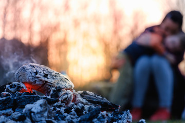 Mother and son sit in the evening at the fire at a picnic