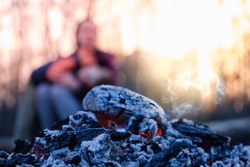 Mother and son sit in the evening at the fire at a picnic