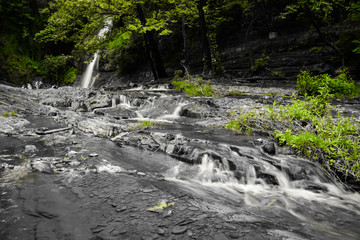 Beautiful waterfall falling to the river in motion under green trees in a sunny day in Georgia