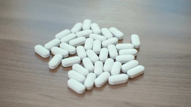 Pale of white pills on the table closeup. Room for text.