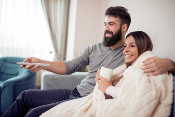 Happy young couple sitting and watching TV at home