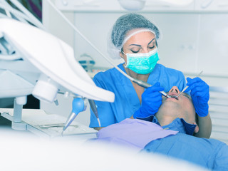 adult dentist checking teeth of patient