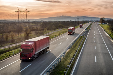 Caravan or convoy of Red Lorry trucks in line on a country highway