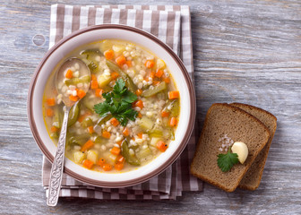 Vegan soup with pickled cucumbers and pearl barley, rassolnik. traditional homemade Russian cuisine. on a wooden table