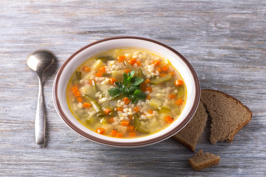 Vegan soup with pickled cucumbers and pearl barley, rassolnik. traditional homemade Russian cuisine. on a wooden table
