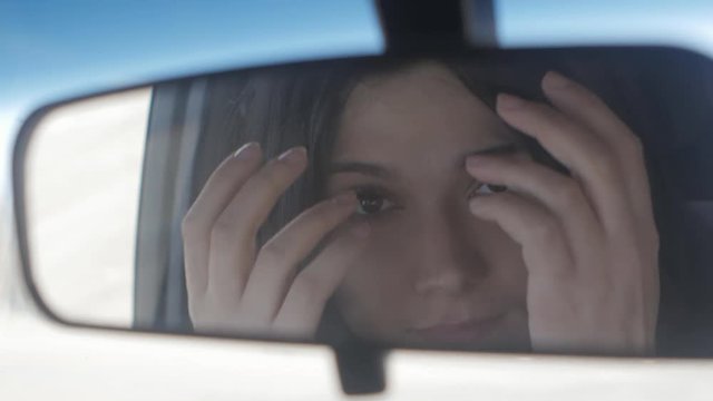 Close up Young beautiful woman looking in rear view mirror while sitting in car
