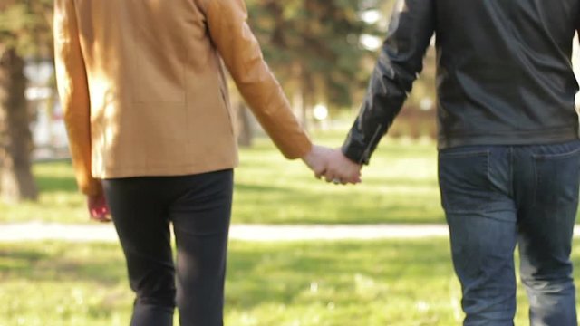 Close-up of a gay couple holding hands and walking in a park