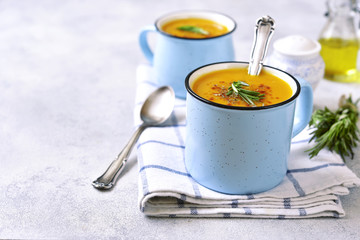 Two portions of pumpkin creamy soup in a blue emamel mugs.