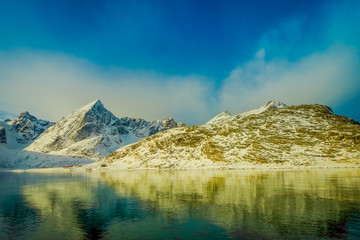 Naklejka premium Gorgeous view of mountain peaks and reflection in water on Lofoten islands