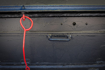 Painted metal surface. A red object on a black background. Metal painted black. The red loop of wire
