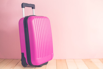 Pink luggage against pastel colored wall background