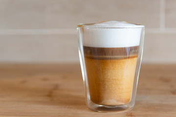 multilayer coffee or cappuccino in a glass cup on wooden table