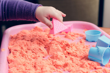The hands of a child playing with kinetic sand