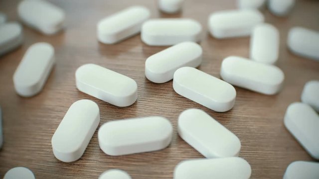 Closeup white oval pills on the table.