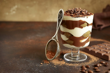 Traditional italian dessert tiramisu with chocolate sauce in a glass.