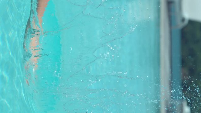 SLOW MOTION, CLOSE UP: Playful female tourist splashes pool water glimmering in the bright summer sunshine. Unknown girl hits and sprays beautiful droplets of pool water. Breathtaking summer holiday.