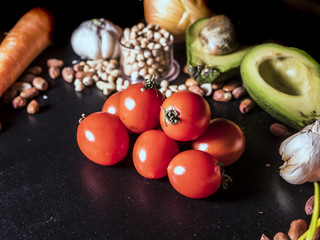 close up shot of raw vegan vegetables with tomato avocado seeds and nuts