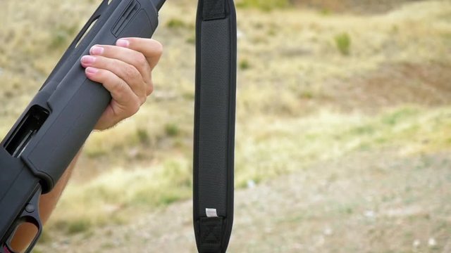 Man ejects a shotgun shell from a smoking gun chamber in slow motion. The Caucasian man pulls back the slide and discharges the cartridge from the pump action weapon. Handheld shot shows gun control.