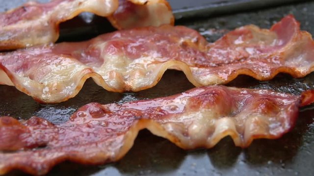Close-up of a slice of bacon fried on a hot grill