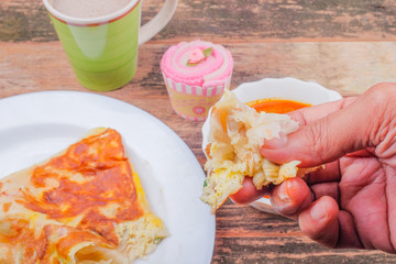 Man holding Roti canai or Roti Parata over wooden  table