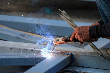 Asian worker making sparks while welding steel