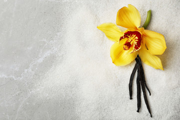 Vanilla sugar with flower and sticks on grey background