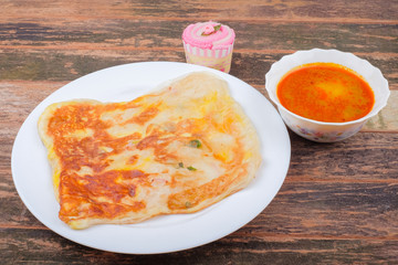 Roti canai or Roti Parata and curry sauce on the plate over wooden  table