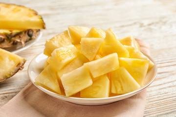 Plate with fresh pineapple slices on wooden background, closeup