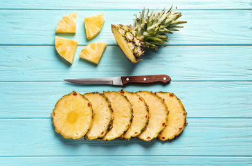Flat lay composition with fresh sliced pineapple and knife on wooden background