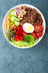 Buddha bowl dish with boiled egg, chickpea, fresh tomato, sweet pepper, cucumber, savoy cabbage, red onion, green sprouts, spinach leaves, chia and quinoa