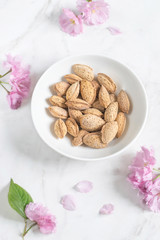 Morning still life with fresh almonds, pink  flowers of almonds on a marble table